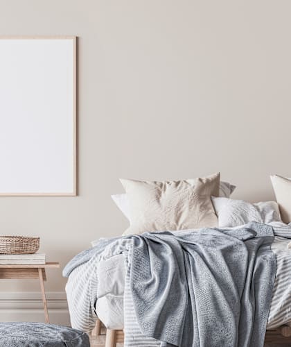a bedroom with a bed and an empty picture frame on the wall