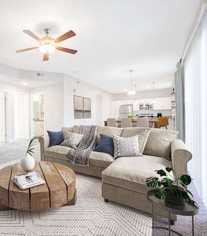 A living room with a couch, a coffee table, and a ceiling fan.
