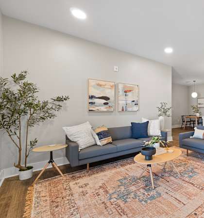A living room with a grey couch, a blue chair, and a rug.