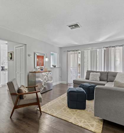 A living room with a grey couch, a wooden chair, and a rug.