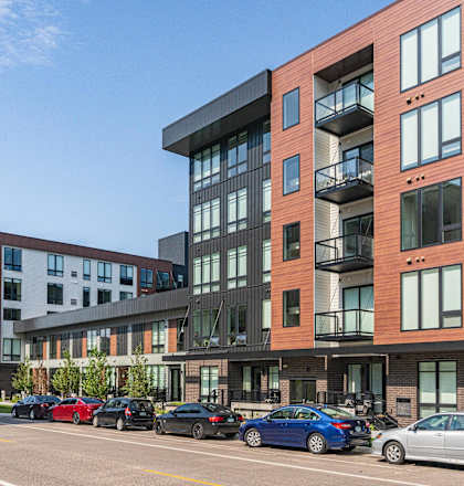 a rendering of a large apartment building with cars parked in front of it