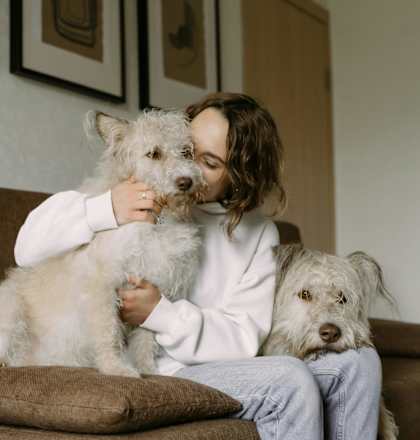 A woman is sitting on a couch with two dogs.