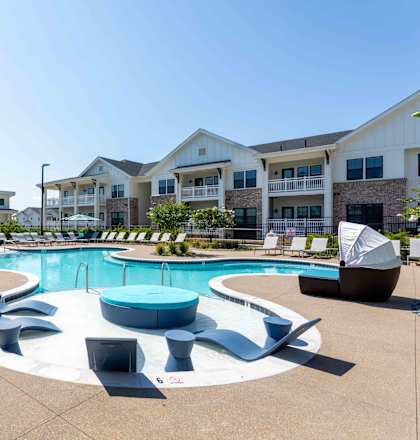 A large outdoor swimming pool surrounded by lounge chairs and umbrellas.