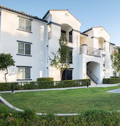 A row of white houses with green lawns in front.