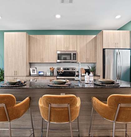 A modern kitchen with a black countertop and chairs.
