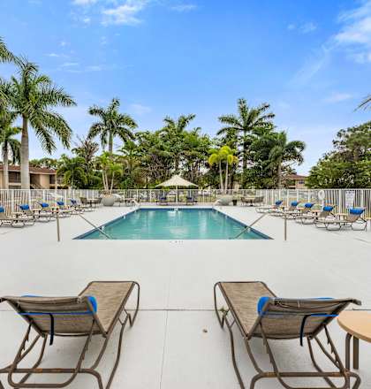 a swimming pool with lounge chairs and umbrellas