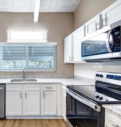 a kitchen with white cabinets and appliances and a window
