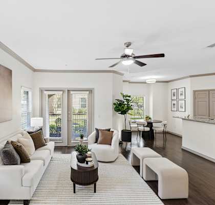 A living room with a white couch and a painting on the wall.