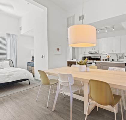 a dining room with a wooden table and chairs and a kitchen with stainless steel appliances