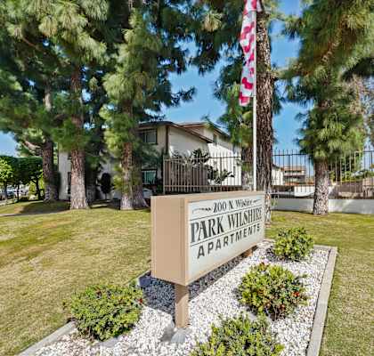 A sign for Park Wilshire Apartments is in front of a building.