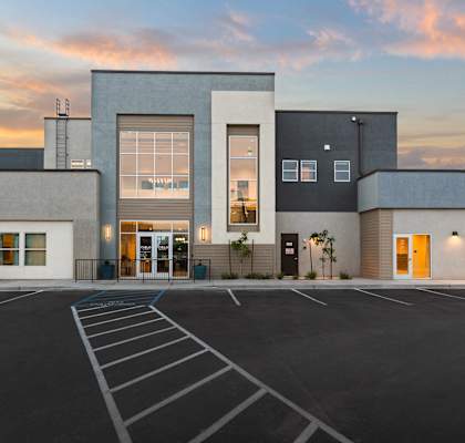 A modern building with a parking lot in front.