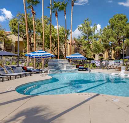 our resort style swimming pool is surrounded by chairs and umbrellas