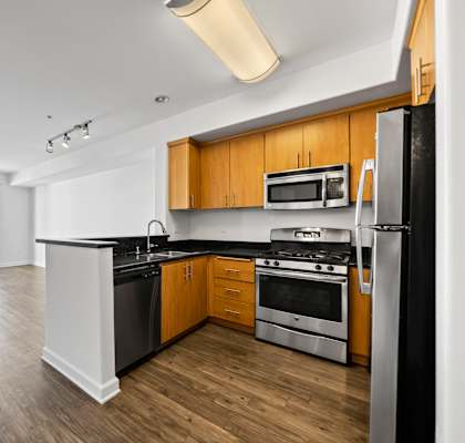 a kitchen with black counter tops and stainless steel appliances and wood floors