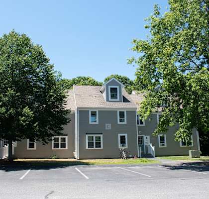 a large gray house with trees in a parking lot