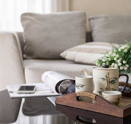 A modern living room with a grey couch, a round table, and a lamp.