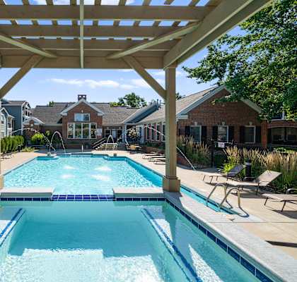 A large swimming pool under a wooden pergola. at Somerset Oaks Apartment Homes, Olathe
