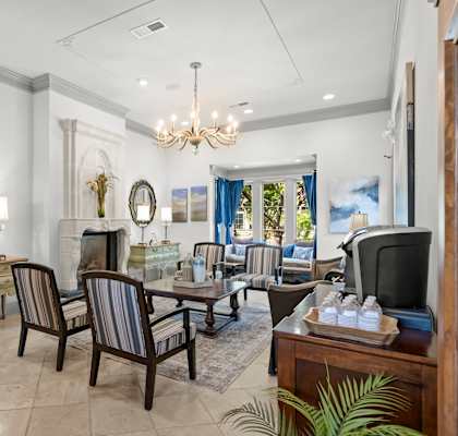 A living room with a chandelier, a couch, a chair, a coffee table, and a television.