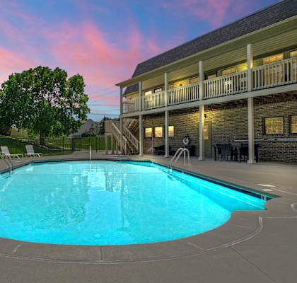 A large outdoor swimming pool in front of a building with a balcony.