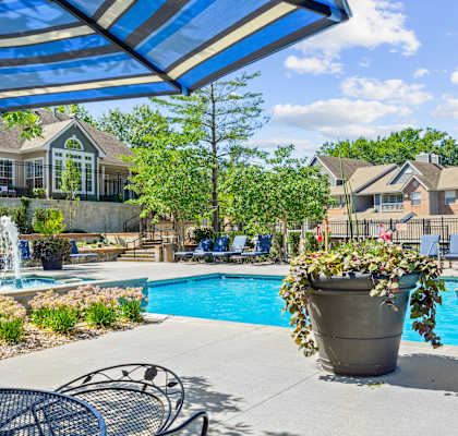 A pool area with a fountain and a patio umbrella.