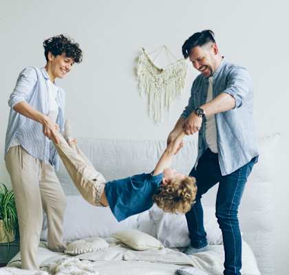 a man and two women are playing with a child on a bed
