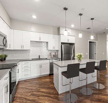 A modern kitchen with a central island and bar stools.
