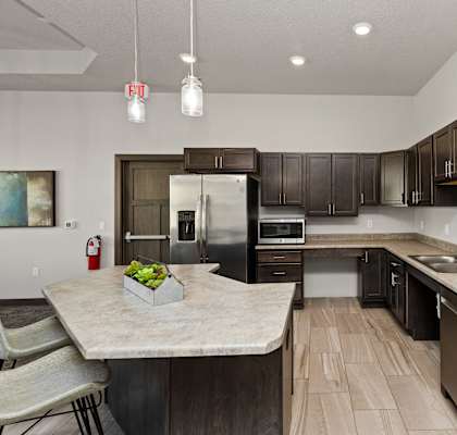 A kitchen with a marble countertop and dark wood cabinets.