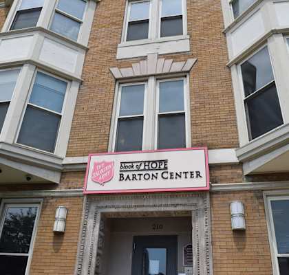 A brick building with a pink sign that says Block of Hope Barton Center.