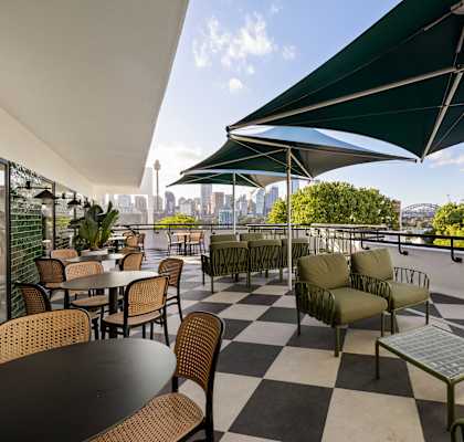 A patio with tables and chairs and a green umbrella.