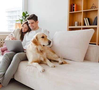 A man and woman sitting on a couch with a dog.