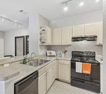 A kitchen with a black oven and white cabinets.