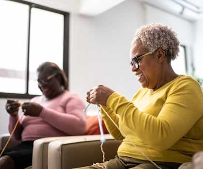 Two women knitting in a bright room.