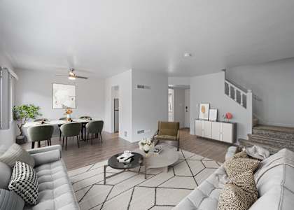 A modern living room with a grey sofa, a coffee table, and a dining table set up.