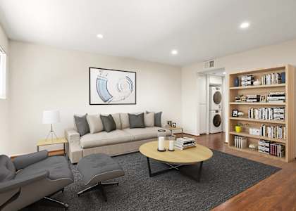 A living room with a grey couch, a grey chair, a black coffee table, a grey rug, a grey carpet, a grey wall, a white ceiling, a white floor, a white door, a white lamp, a white