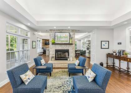 A living room with a fireplace and blue chairs.