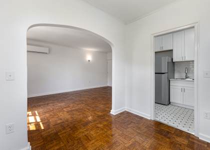 A kitchen with white cabinets and a wooden floor.
