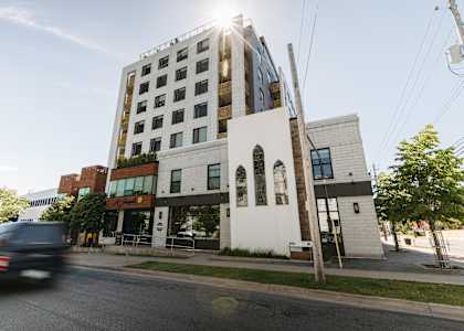 A modern building with a white facade and a black car driving by.