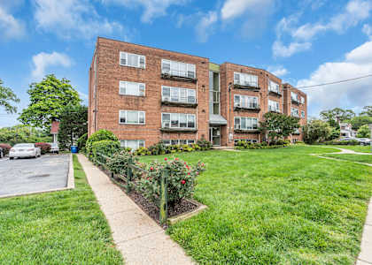 A red brick apartment building with a green lawn in front.