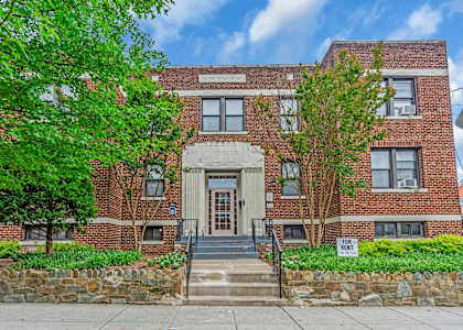 A red brick building with a stone wall in front.