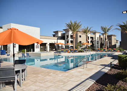 A pool area with a table and chairs and umbrellas.