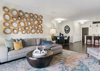 A modern living room with a grey couch and a large circular wall art.