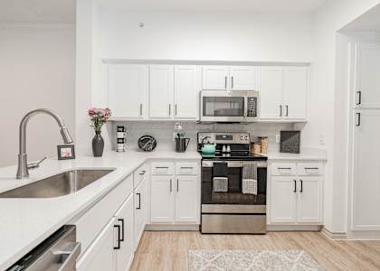 a spacious kitchen with white cabinets and stainless steel appliances