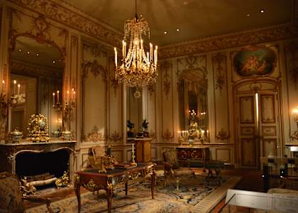 a chandelier hangs from the ceiling in a room with ornate furniture and a fireplace