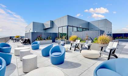 an outdoor patio with chairs and stools on a sunny day