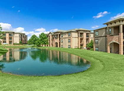 an apartment complex with a pond in front of it