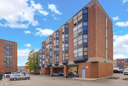 A large brick building with a parking lot in front at Fullerton Court Apartments, Chicago, IL 60614