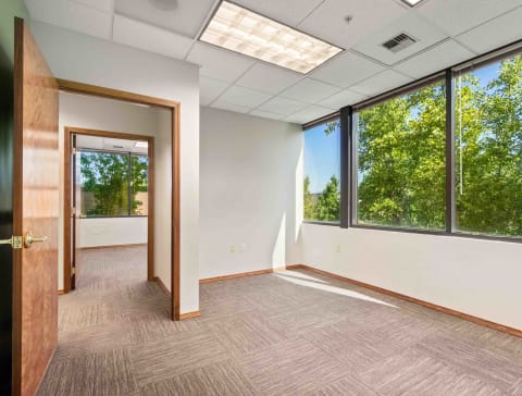 an empty office space with large windows and a door