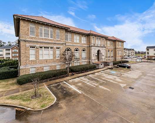 an empty parking lot in front of a large brick building