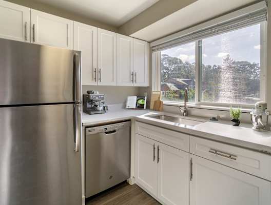 a kitchen with white cabinets and a large window