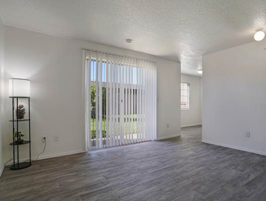 A room with a wooden floor and a window with blinds.