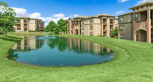 an apartment complex with a pond in front of it